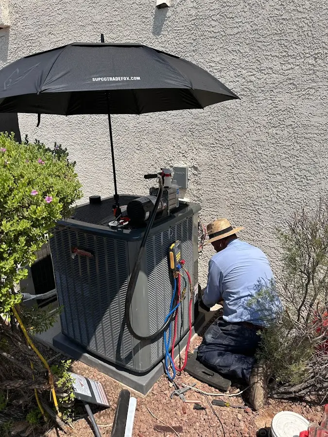 HVAC technician performing outdoor AC maintenance in Kenwood